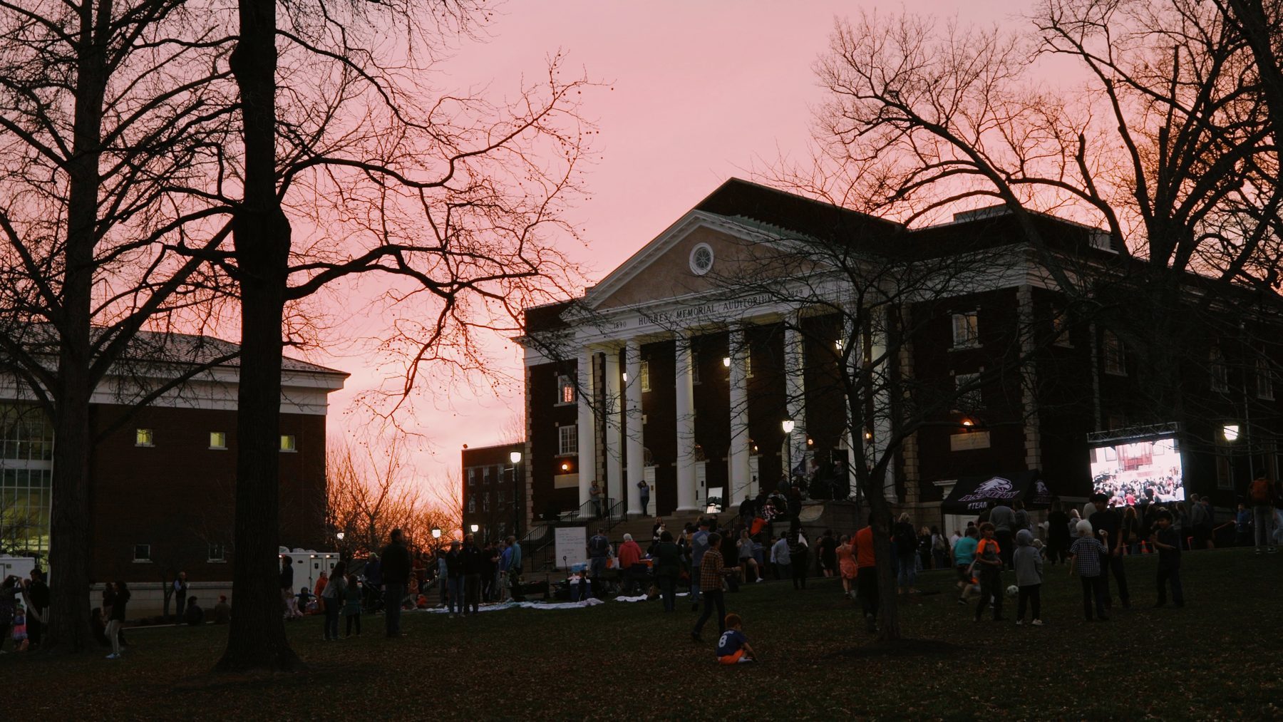 The lawn in front of Hughes Auditorium at sunset, with a crowd gathered on the grass