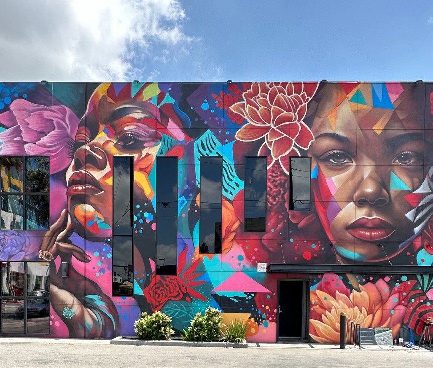 Wide view of the Granville mural showing two painted faces across the building facade