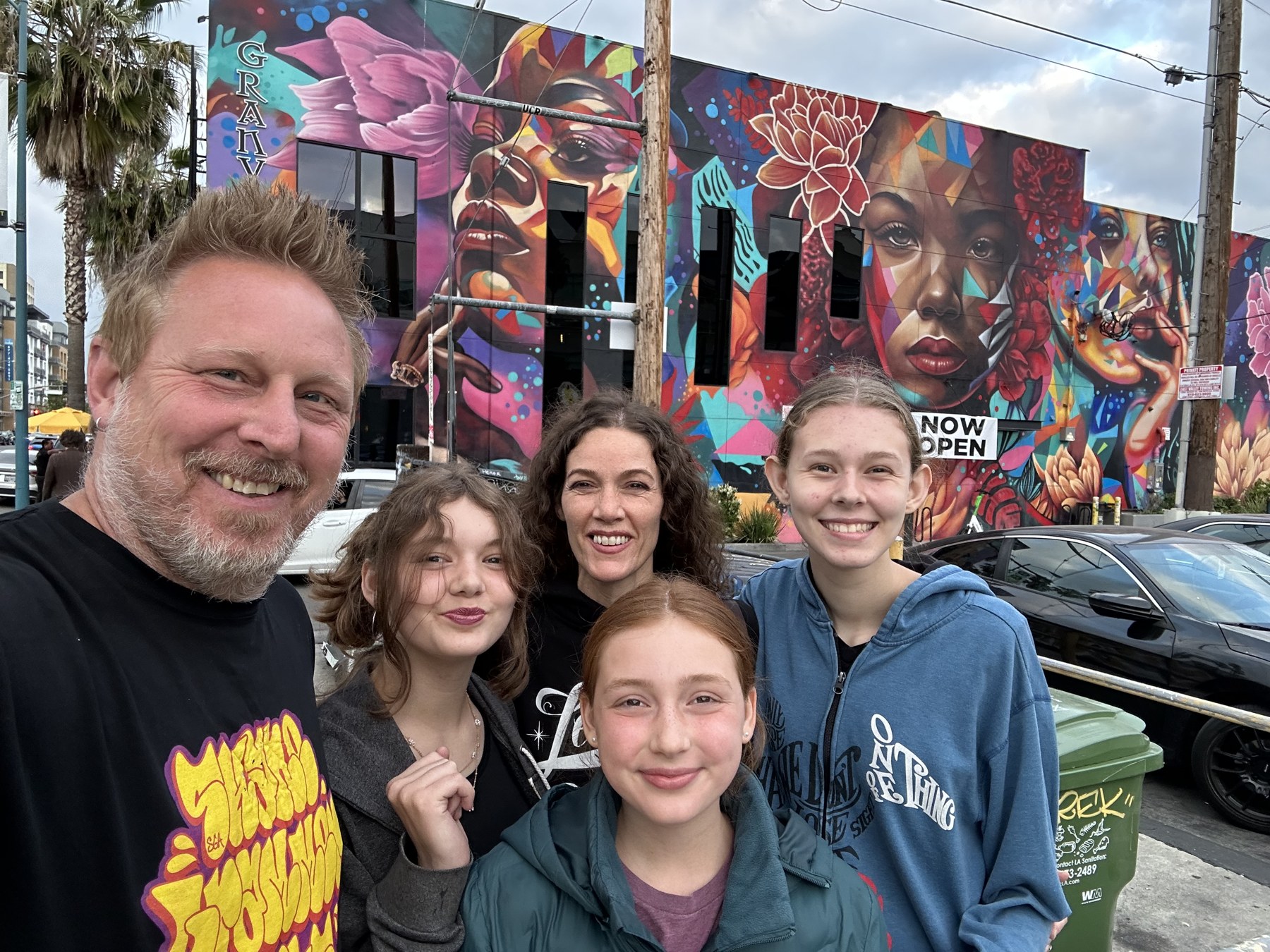 Shane Grammer with his wife and three daughters in front of the Granville mural